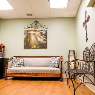 A cozy waiting area featuring a decorative sofa, artwork on the walls, and ample natural light.