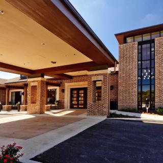 A modern building entrance with a large overhanging roof and brick facade.