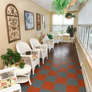 A bright and welcoming interior waiting area with wicker chairs, tables, and plants near large windows.