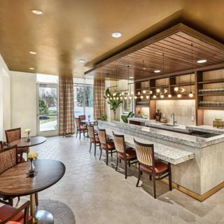 A modern restaurant interior featuring a stylish bar area with counter seating and elegant lighting fixtures.