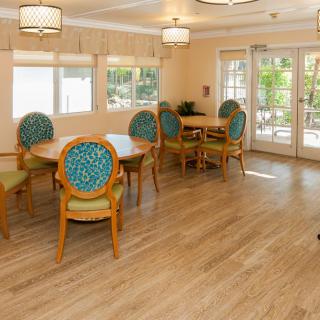 A bright and inviting dining area with wooden flooring, round tables, and cushioned chairs.
