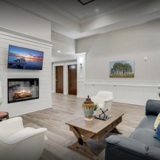 A modern living room featuring a fireplace and television, with elegant seating and artwork adorning the walls.