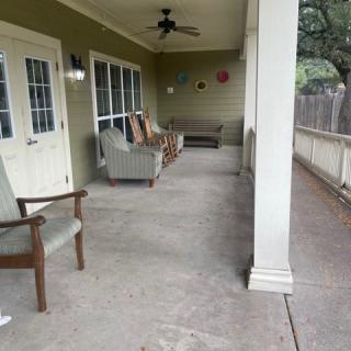 A spacious outdoor porch with seating and a ceiling fan.