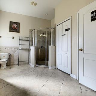 A spacious and modern bathroom with a glass shower enclosure and tiled flooring.