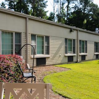 A view of a modern building exterior with multiple windows, surrounded by well-maintained grass and garden.