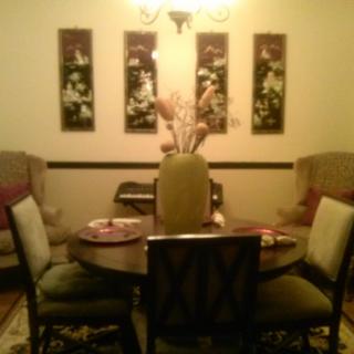 A cozy dining room featuring a round table surrounded by chairs, with artwork adorning the walls.