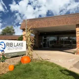 Entrance to a building with autumn decorations and a sign for Rib Lake.