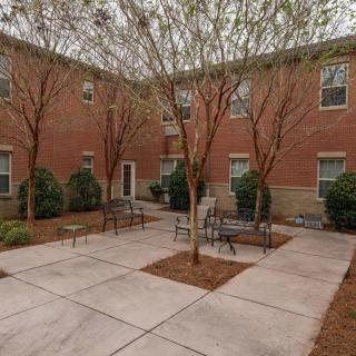 A quiet courtyard featuring benches and trees surrounded by a brick building.