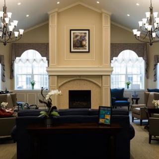A spacious living room featuring a prominent fireplace, elegant chandeliers, and comfortable seating with large windows.