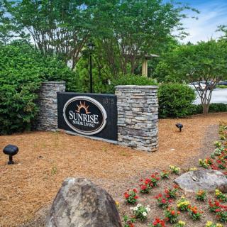 A landscaped entrance with a stone wall and vibrant flowers surrounding the sign.