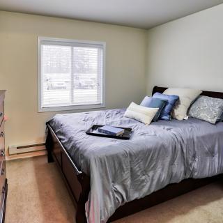 A cozy bedroom with a neatly made bed and pillows near a window.
