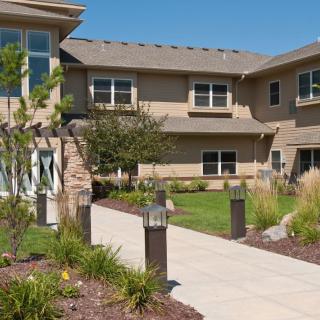 A modern residential building with a landscaped garden and pathway.