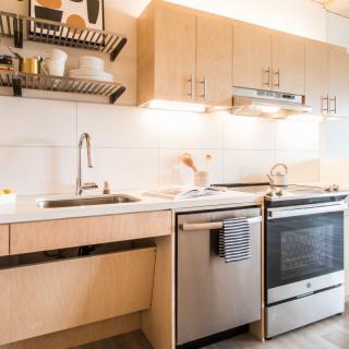 A modern minimalist kitchen with wooden cabinets and stainless steel appliances.