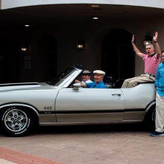 A group of people enjoying a ride in a vintage convertible car.