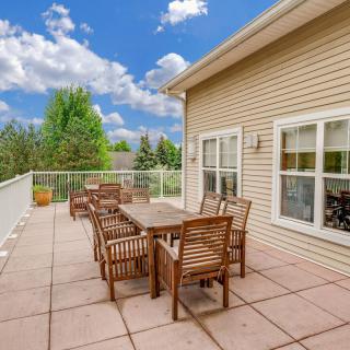A spacious outdoor patio with wooden furniture under a bright blue sky.
