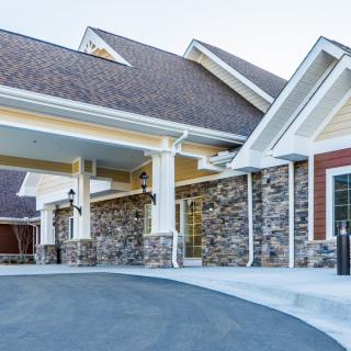 A modern building entrance featuring a stone facade and covered driveway.