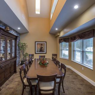 Elegant dining room with a long table, chairs, and large windows.