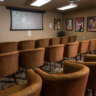 A cozy home theater setup with comfortable seating and a projector screen, surrounded by movie posters.