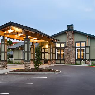 A well-lit building entrance with a covered walkway and stone accents in the evening.