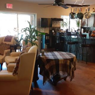 A cozy living room space featuring a comfortable couch, a table covered with a plaid cloth, and an open view into the kitchen area.