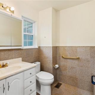 A clean and simple bathroom with a sink, toilet, and mirror.