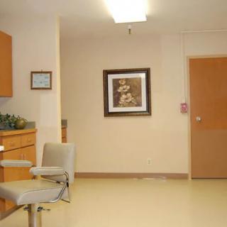 A view of a clinic waiting room with chairs and framed artwork on the wall.