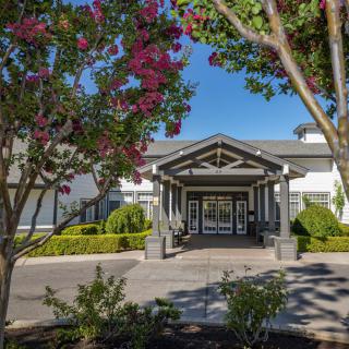 A well-maintained building entrance surrounded by lush landscaping and blooming trees.