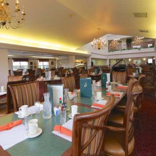 A spacious restaurant dining area with elegantly arranged tables and chandeliers.