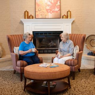 Two seniors having a conversation over coffee in a cozy living room setting.