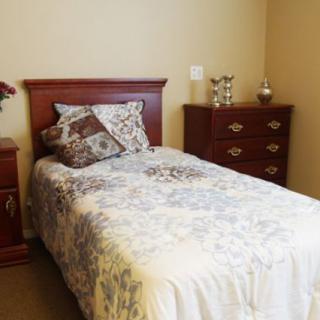 A cozy bedroom with a single bed and floral bedding, complemented by wooden furniture.