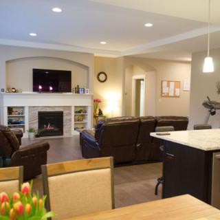 A modern open-concept living room with a fireplace and comfortable seating, connected to a dining area.
