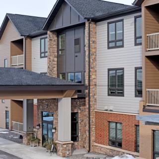 A modern residential apartment building with a mix of brick and siding materials.
