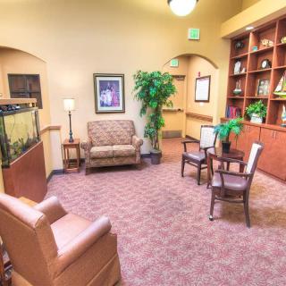 A cozy lobby area with comfortable seating, a bookshelf, and decorative plants.