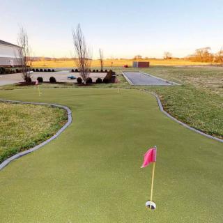 A well-maintained outdoor putting green with a bright red flag set against a clear sky.