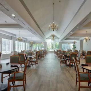 A spacious dining room with elegant chandeliers and neatly arranged tables and chairs.