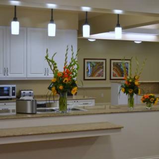 A modern kitchen interior featuring decorative flowers on the countertop and stylish lighting fixtures.