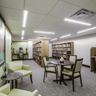 A cozy library area with bookshelves, tables, and chairs for reading.