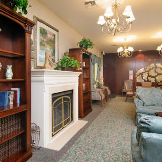 A cozy living room featuring a warm fireplace, elegant furniture, and book-filled shelves.