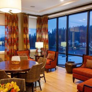 A cozy living and dining area with large windows overlooking a scenic evening view.