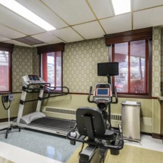 A small indoor gym with a treadmill and stationary bike near the windows.