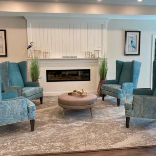 A cozy living room with teal armchairs and a fireplace.