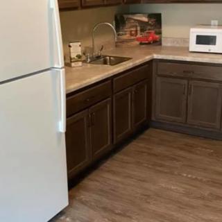 A kitchen area featuring a refrigerator, microwave, and wooden cabinets.