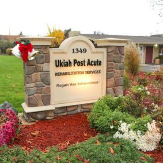 A stone sign for Ukiah Post Acute Rehabilitation Center surrounded by landscaped gardens and holiday decorations.