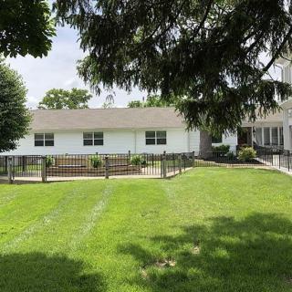 A suburban house with a large green lawn and surrounding trees.