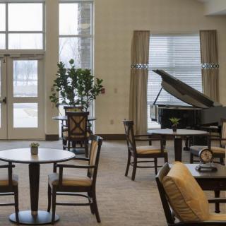 A spacious lobby area with a grand piano, tables, and chairs.
