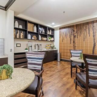 A cozy dining area with modern decor, featuring wooden flooring and neatly arranged shelves.