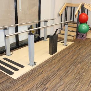 A rehabilitation setup featuring a balance bar and staircase, designed for physical therapy exercises.