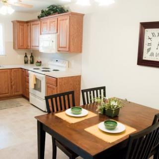 A cozy kitchen and dining area featuring wooden cabinets and a neatly set table.