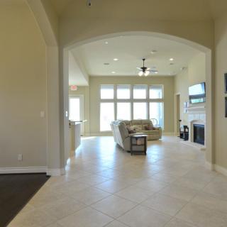 A spacious living room with large windows, tile flooring, and a cozy seating area by the fireplace.