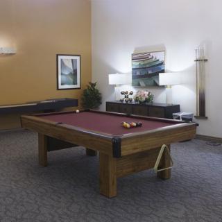 A stylish game room featuring a pool table with red felt, surrounded by modern decor and lighting.